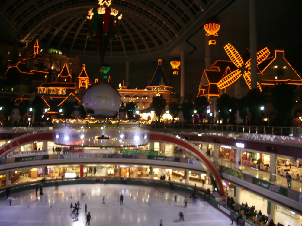 Inside Lotte World Adventure, where the indoor ice rink sits beneath a glass dome ringed by fairytale facades. — Photo: InSapphoWeTrust from Los Angeles, California, USA (CC BY-SA 2.0)