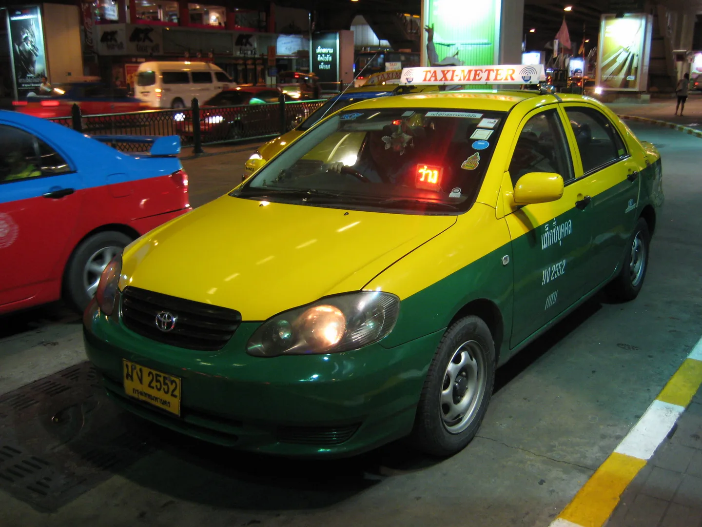 A yellow-green Bangkok metered taxi with its Taxi-Meter roof sign — insist on the meter — Photo: Terence Ong (CC BY 2.5)